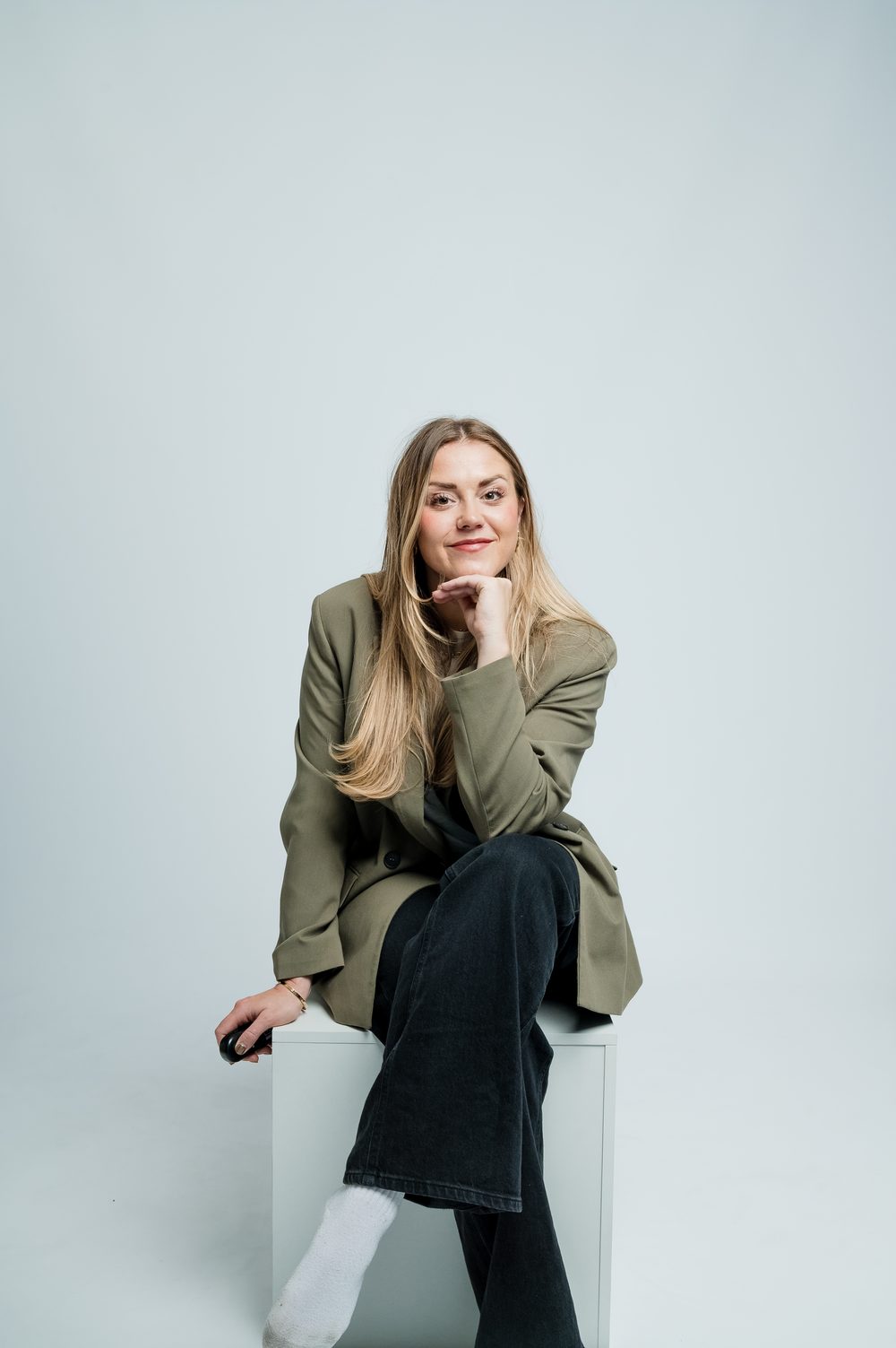 Emily from Breakaway 51 sitting on a white block in a khaki blazer